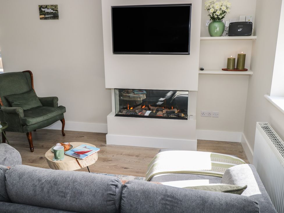 A living room with a fireplace and television at Doire Fhatharta Beag, Carraroe, County Galway
