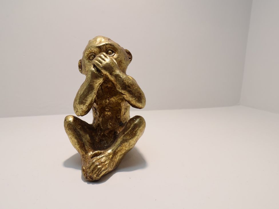 A golden monkey statue sitting with hands covering its face at Sea View House in Marske-By-The-Sea