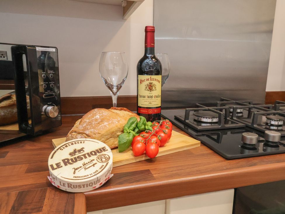 A kitchen with a loaf of bread, wine bottle, cheese, tomatoes and wine glass at Sea View House in Marske-By-The-Sea
