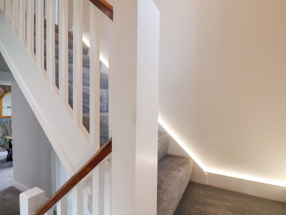 A staircase with a handrail and wall lighting at Sea View House in Marske-By-The-Sea