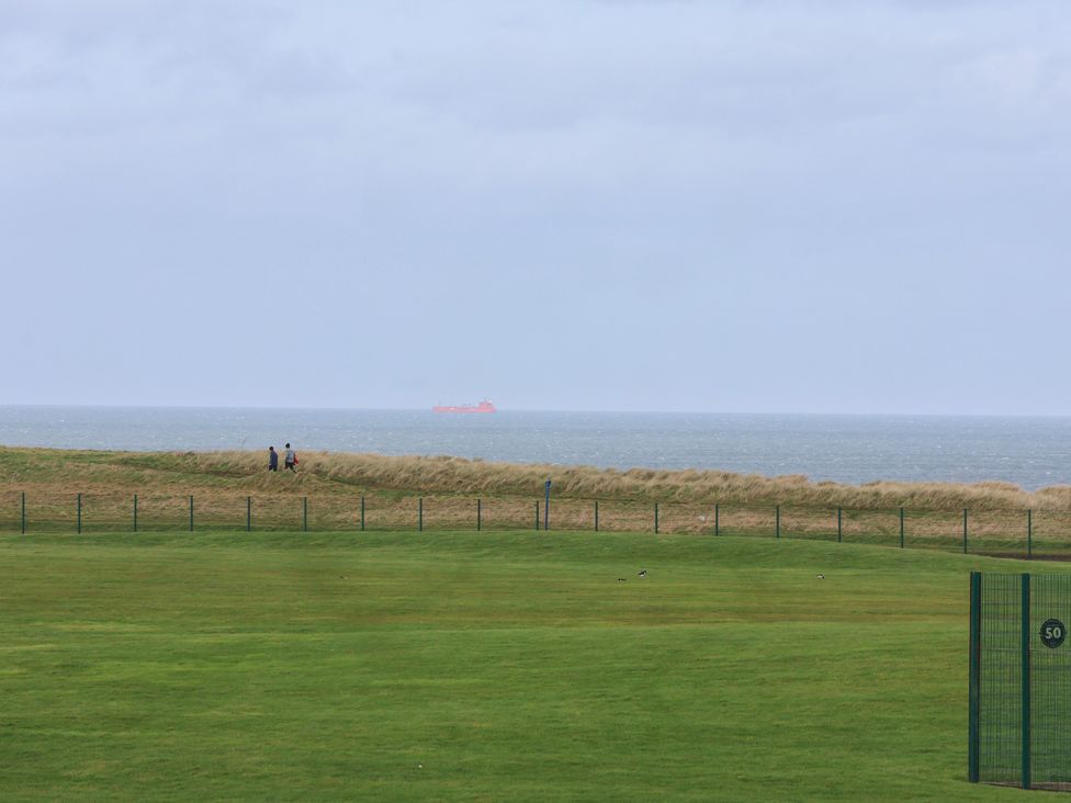 A view of the sea with people walking along the shoreline at Sea View House in Marske-By-The-Sea