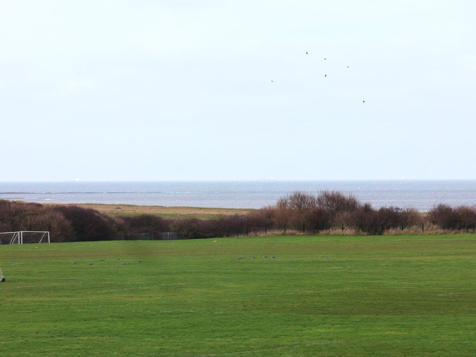 A grassy field with goalposts and a view of the sea at Sea View House in Marske-By-The-Sea