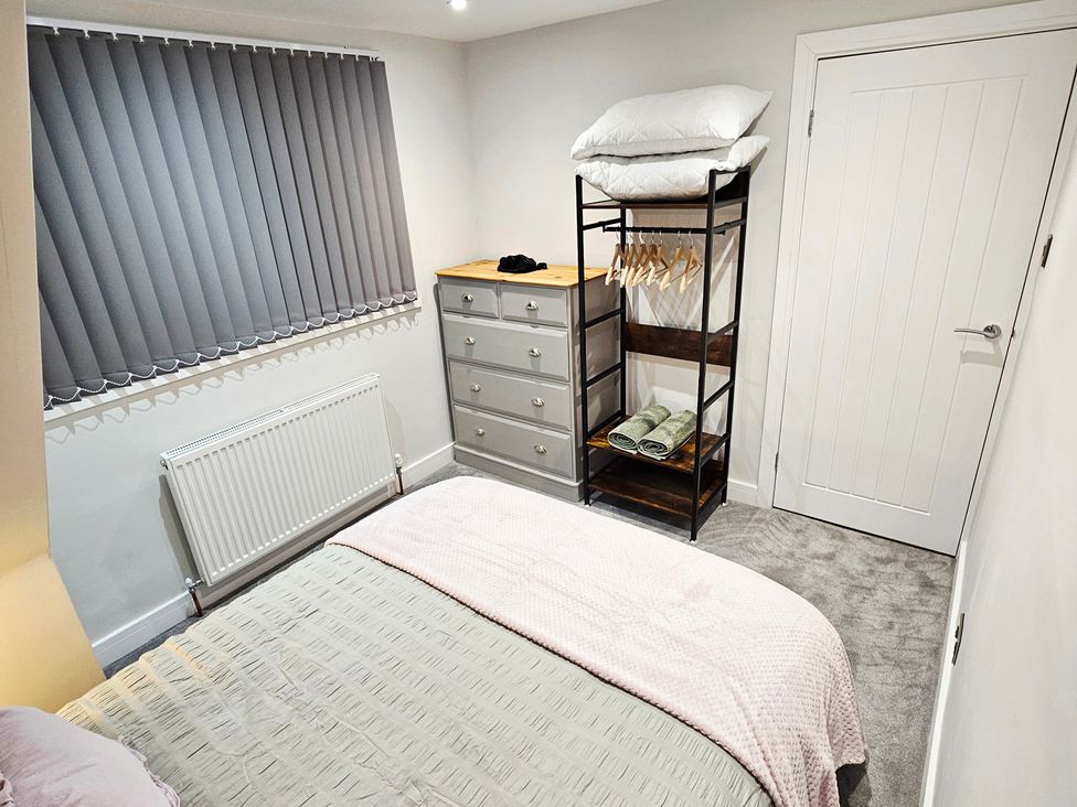 A bedroom with a bed, dresser, and shelves at Sea View House in Marske-By-The-Sea