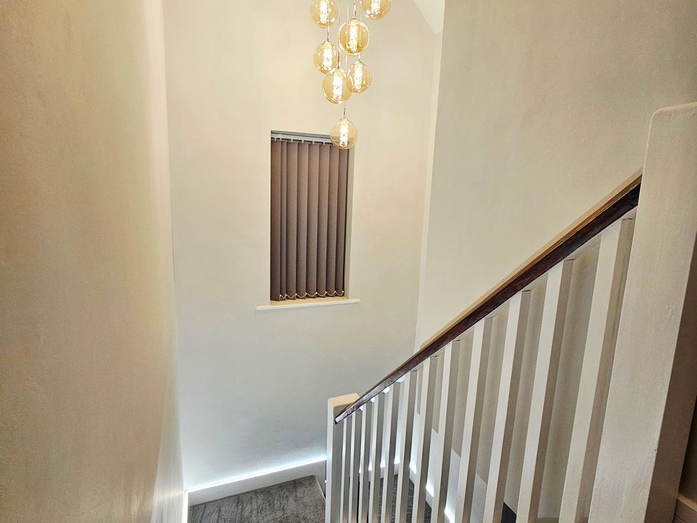 A staircase with a light fixture and window at Sea View House in Marske-By-The-Sea