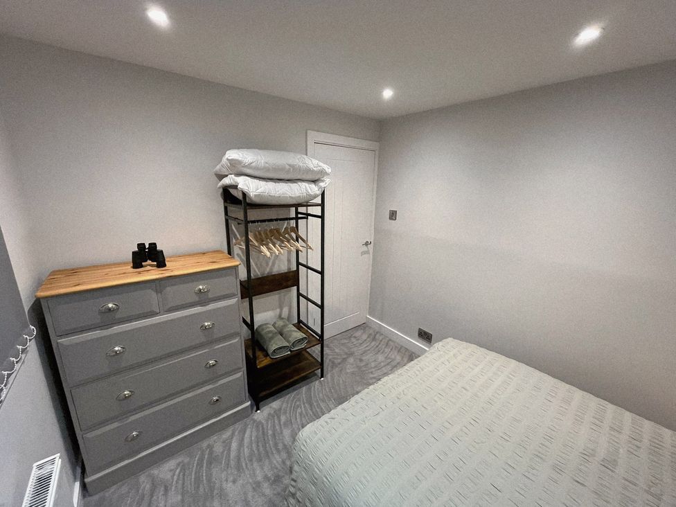 A bedroom with a bed, dresser, and clothes rack at Sea View House, Marske-By-The-Sea