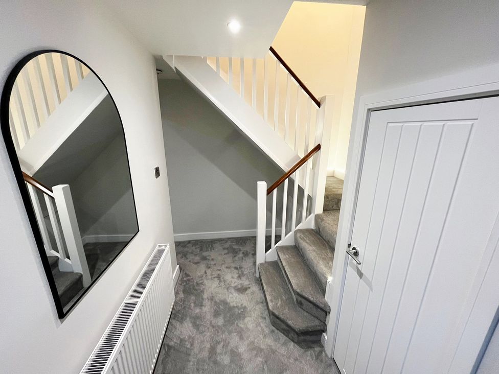 A hallway with a staircase and a mirror at Sea View House in Marske-By-The-Sea