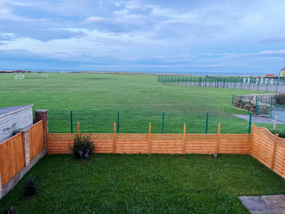 A garden with a fence overlooking a sports field at Sea View House in Marske-By-The-Sea