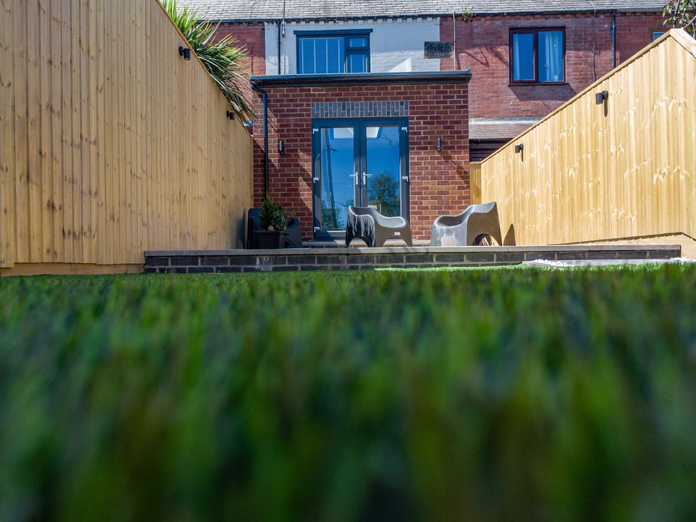 A garden with glass doors and outdoor furniture at 4 Bryn Heulog in Wrexham