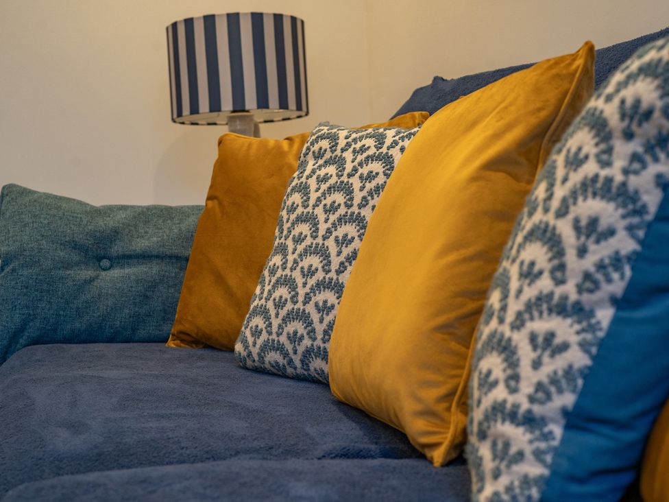 A sofa with cushions and a lamp at 4 Bryn Heulog in Wrexham