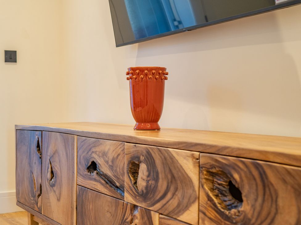 A wooden cabinet with a vase and television at 4 Bryn Heulog in Wrexham