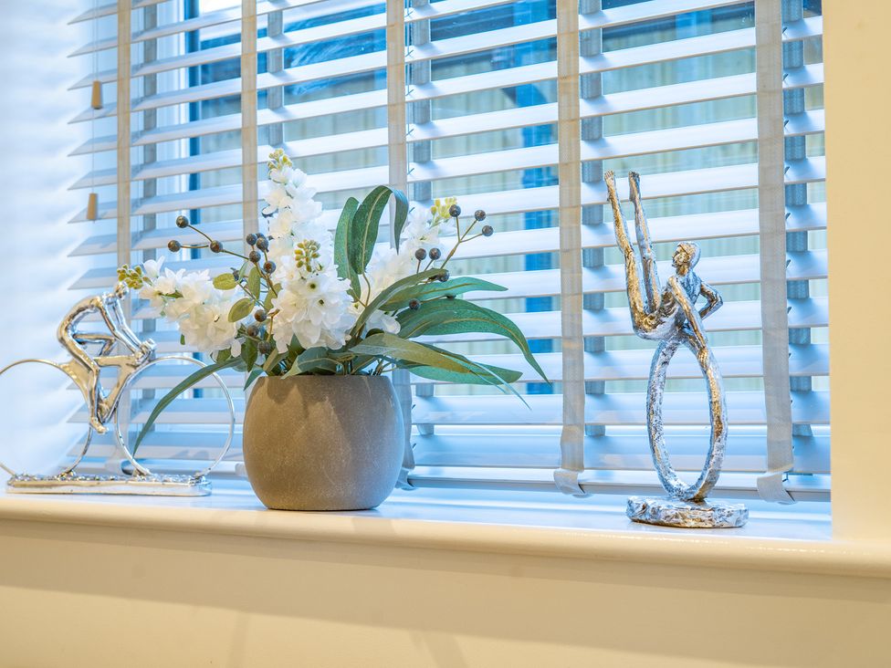 A window sill with a flower arrangement and decorative figurines at 4 Bryn Heulog in Wrexham