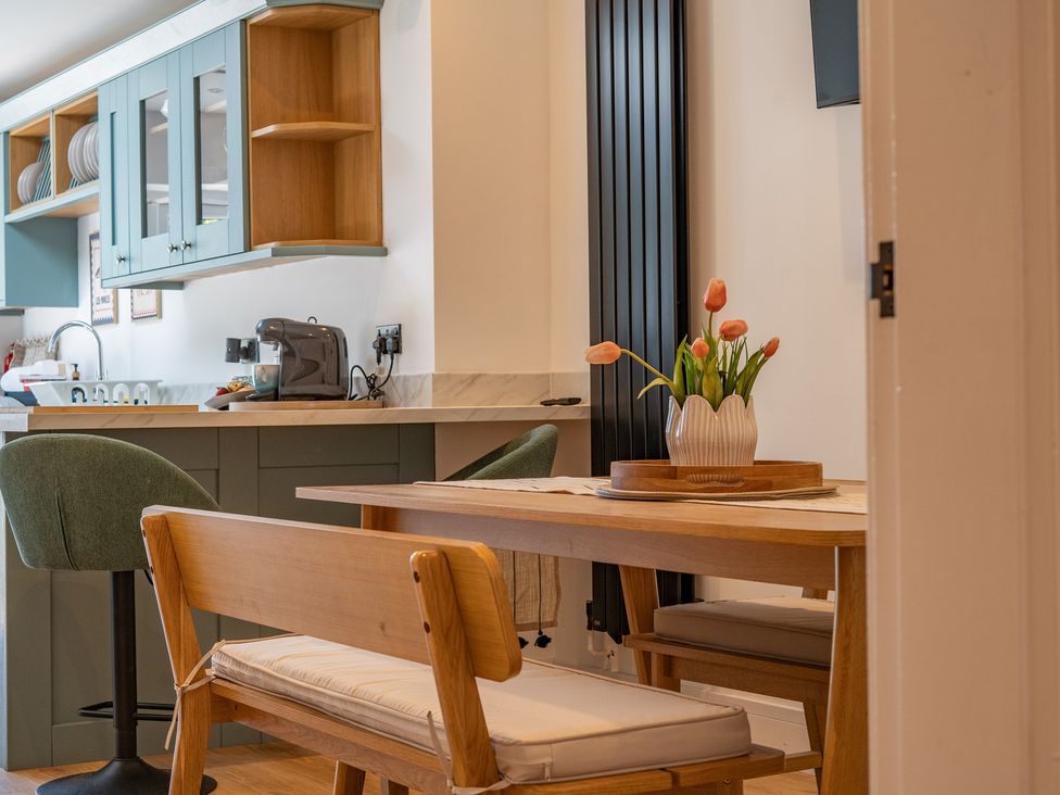 A kitchen with a table and chairs and flowers at 4 Bryn Heulog Wrexham