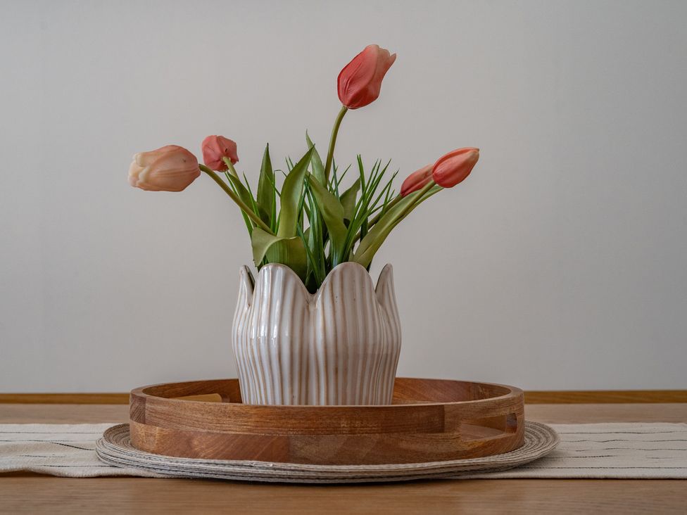 A vase with tulips on a wooden tray with a table runner at 4 Bryn Heulog in Wrexham