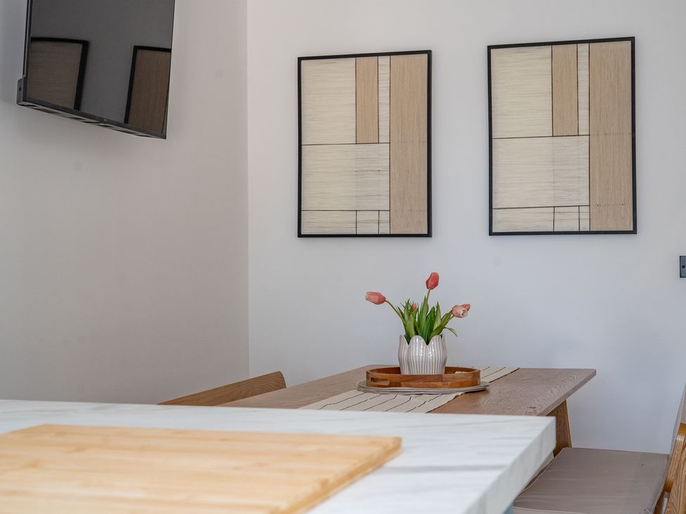 A dining room with a table and flowers in a vase at 4 Bryn Heulog in Wrexham