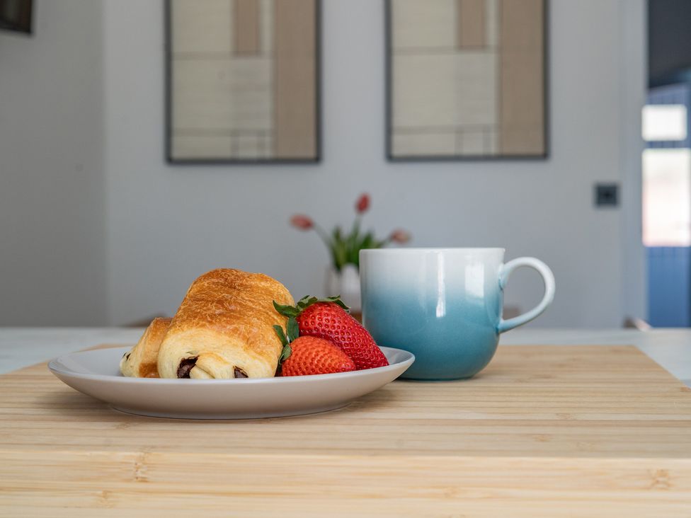 A croissant and strawberries with a coffee cup on a wooden board at 4 Bryn Heulog Wrexham