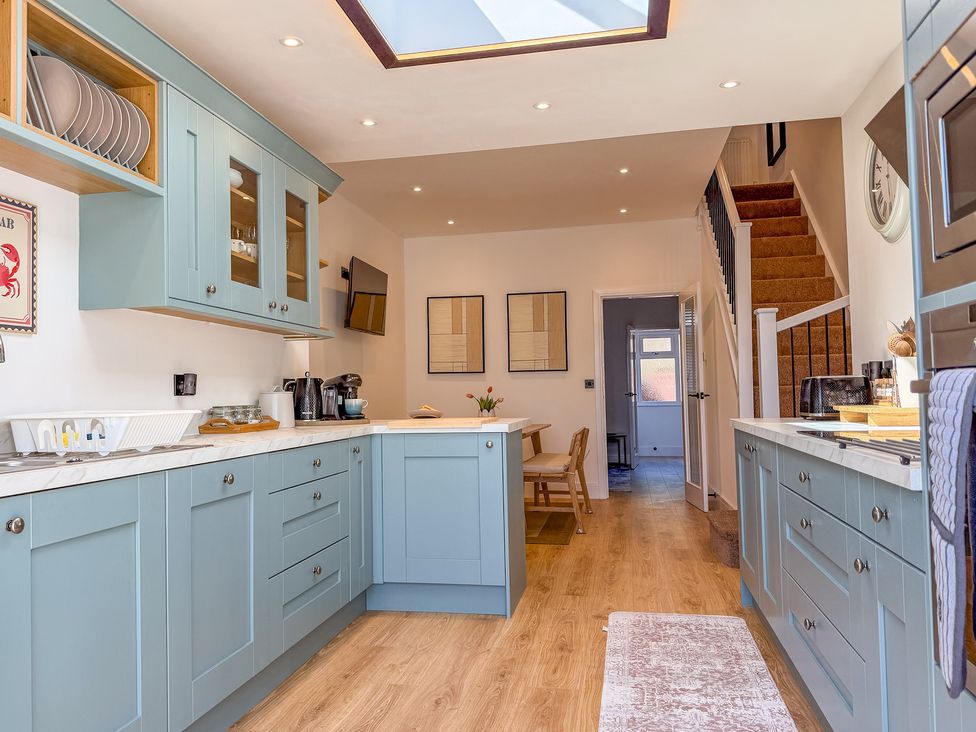 A kitchen with cabinets and a dining table at 4 Bryn Heulog in Wrexham