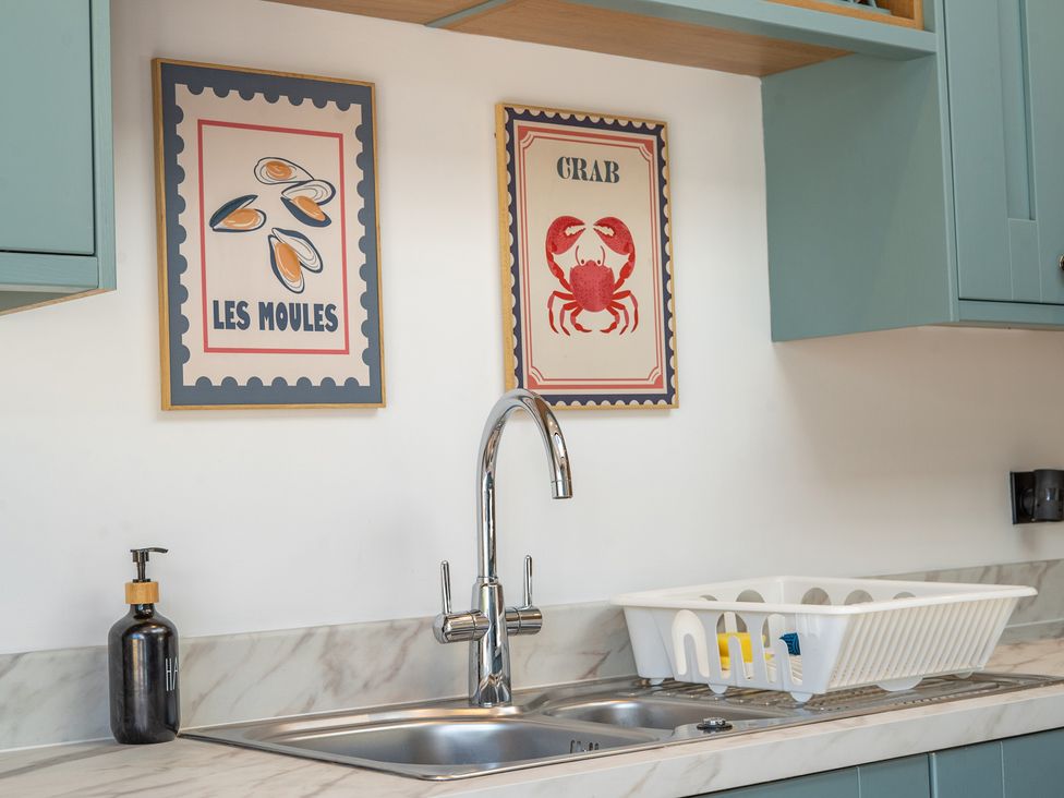 A kitchen with a sink and wall art at 4 Bryn Heulog in Wrexham