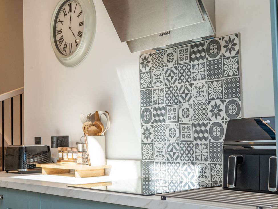 A kitchen with a clock, hood, tiles, and utensils at 4 Bryn Heulog, Wrexham