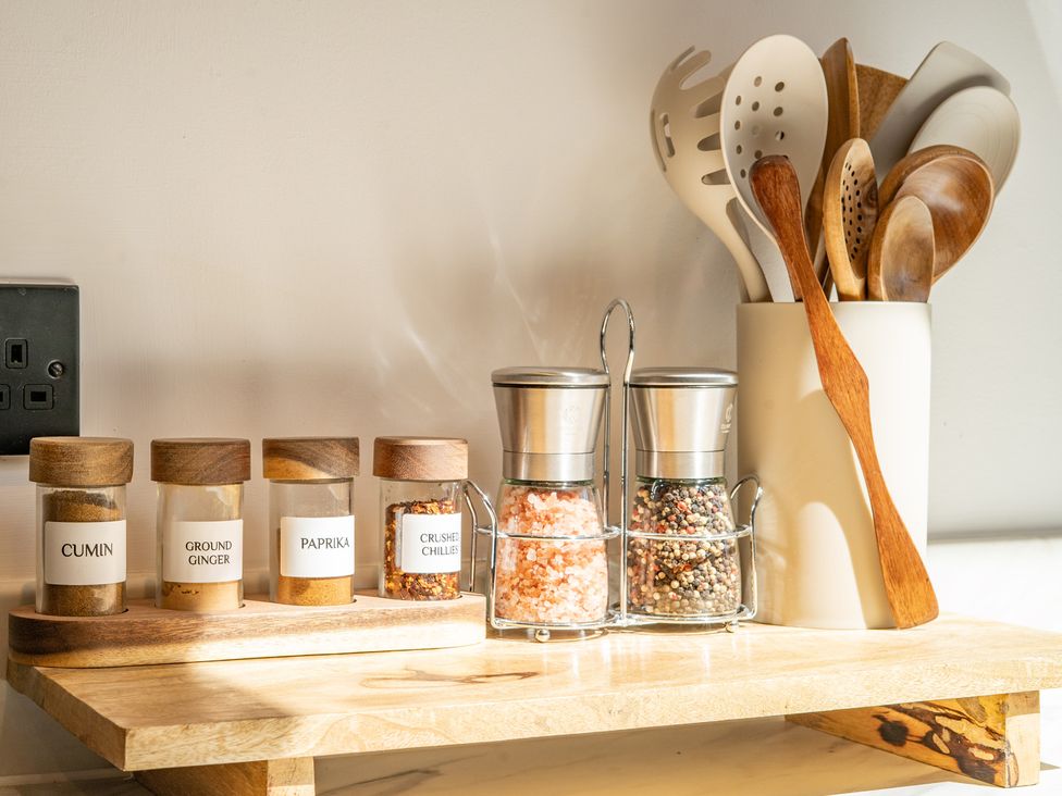 A collection of spice jars and utensils on a kitchen shelf at 4 Bryn Heulog Wrexham
