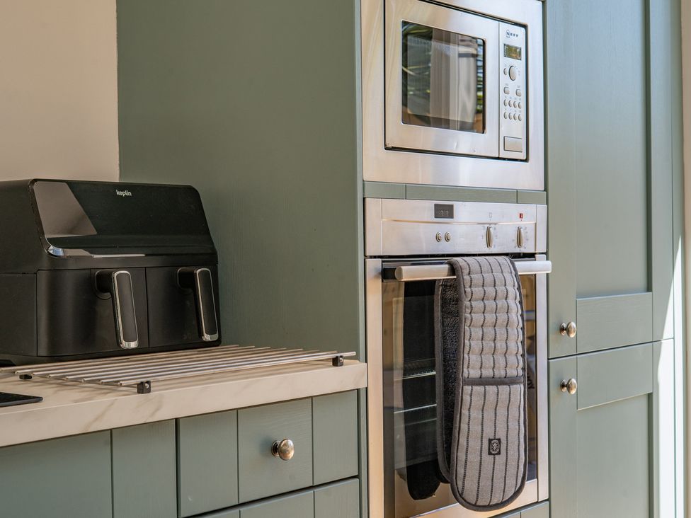 A kitchen with a microwave, oven, and drying rack at 4 Bryn Heulog in Wrexham