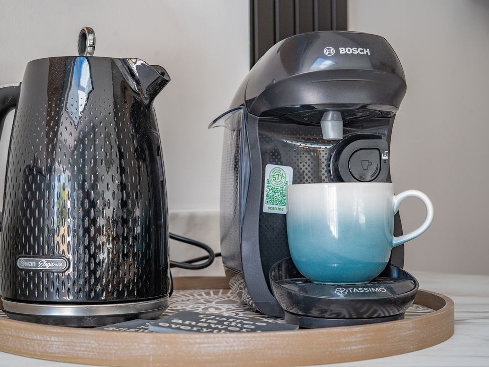 A kettle and coffee machine with a cup on a tray at 4 Bryn Heulog in Wrexham