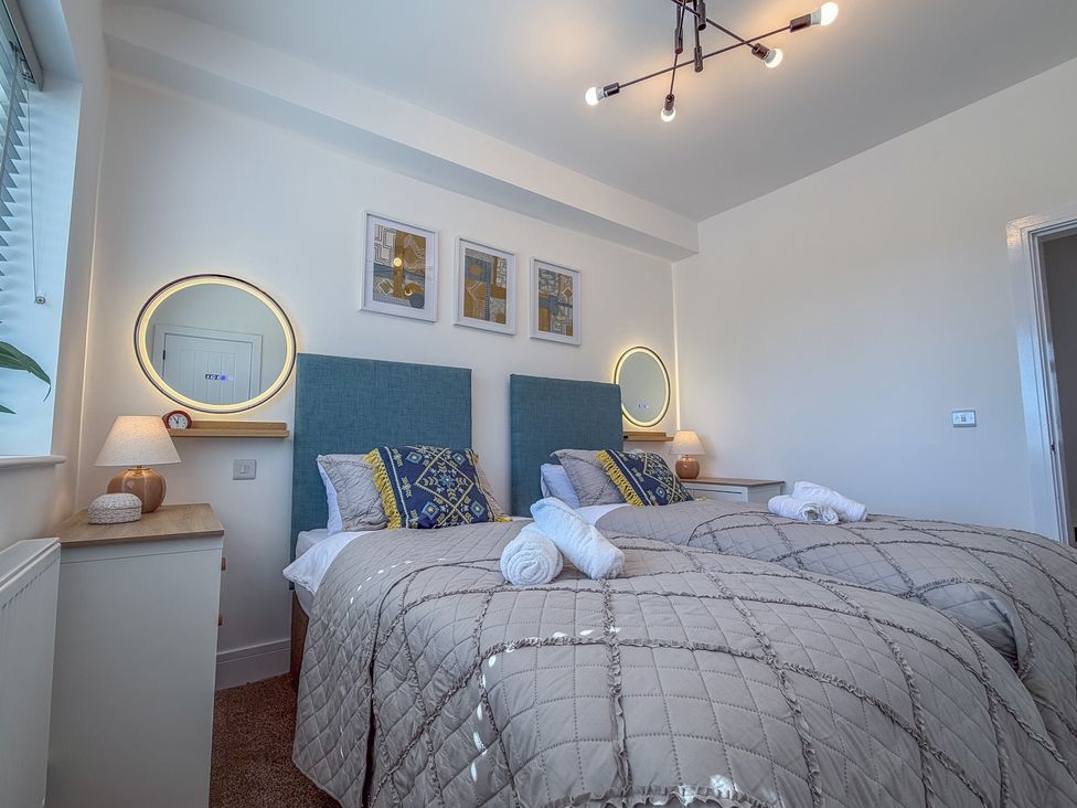 A bedroom with twin beds and a decorative wall at 4 Bryn Heulog in Wrexham