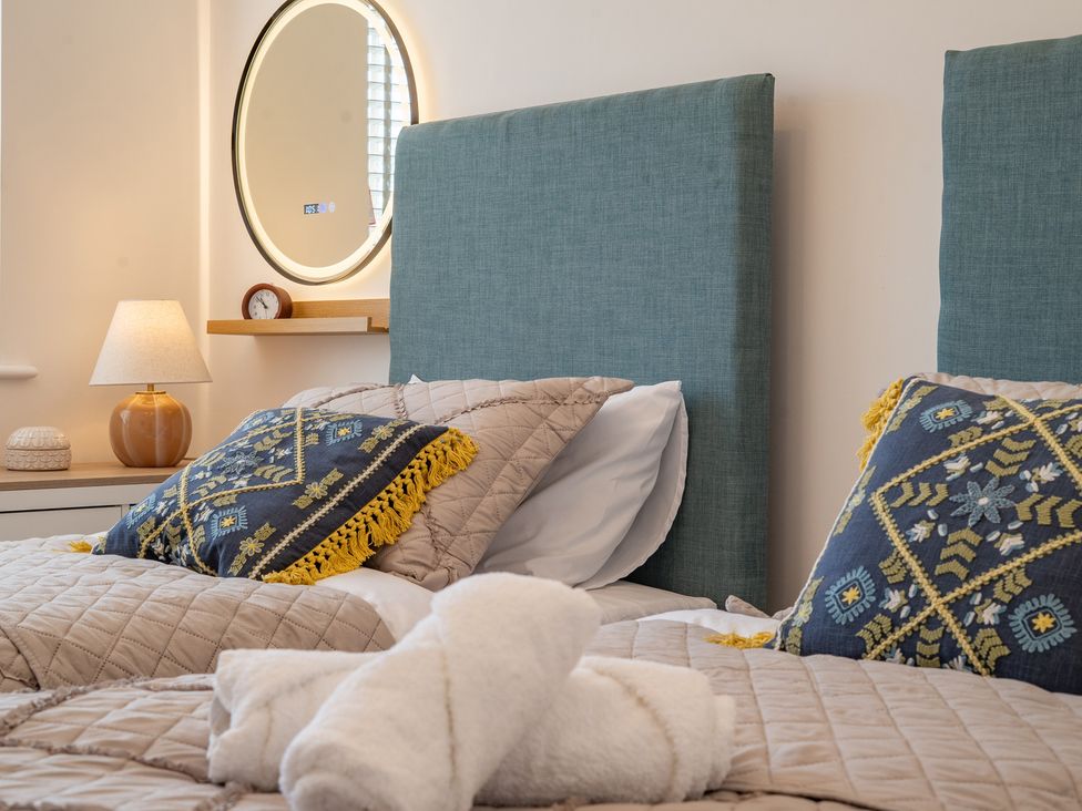 A bedroom with two beds, pillows, and a lamp at 4 Bryn Heulog in Wrexham