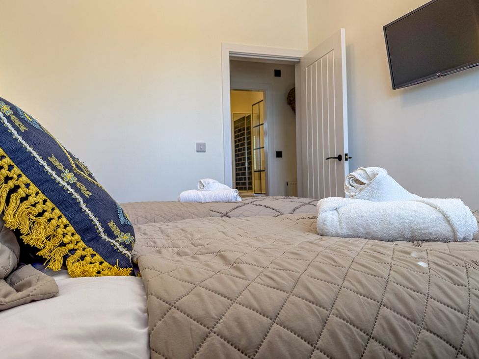 A bedroom with a bed and towels laid at 4 Bryn Heulog Wrexham