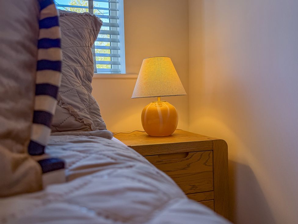 A bedroom with a lamp on a nightstand at 4 Bryn Heulog in Wrexham