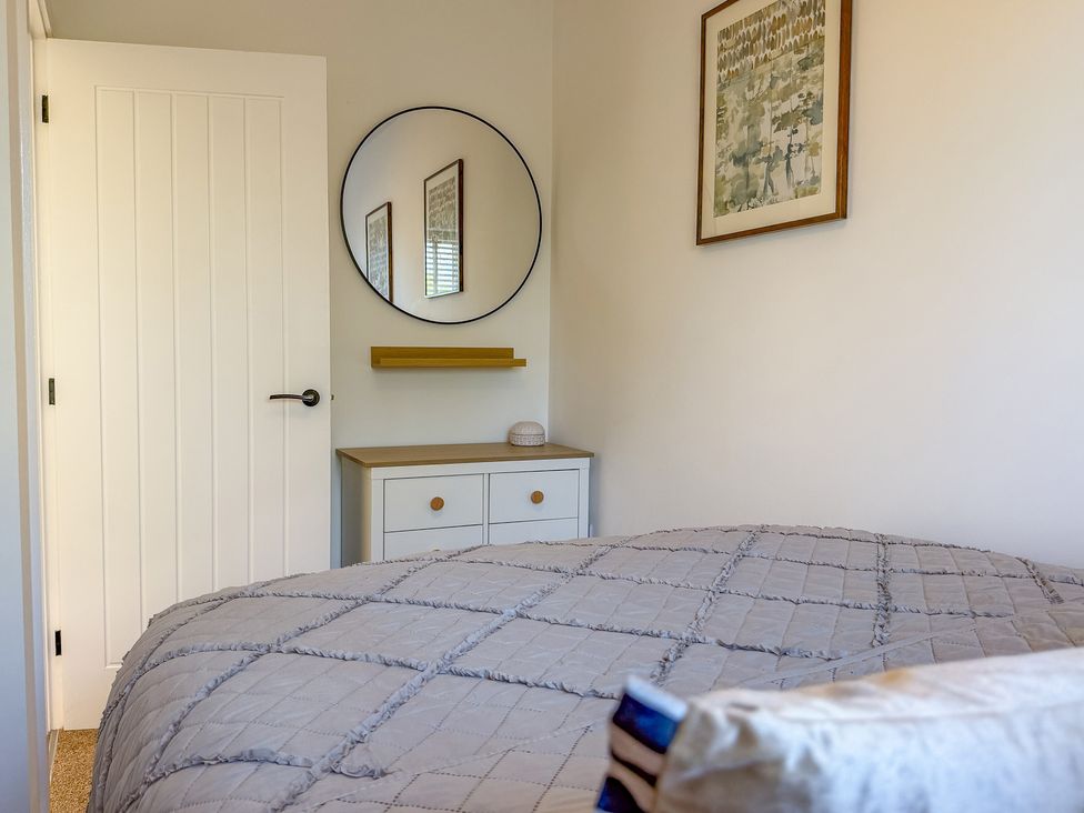 A bedroom with a bed and a mirror at 4 Bryn Heulog in Wrexham