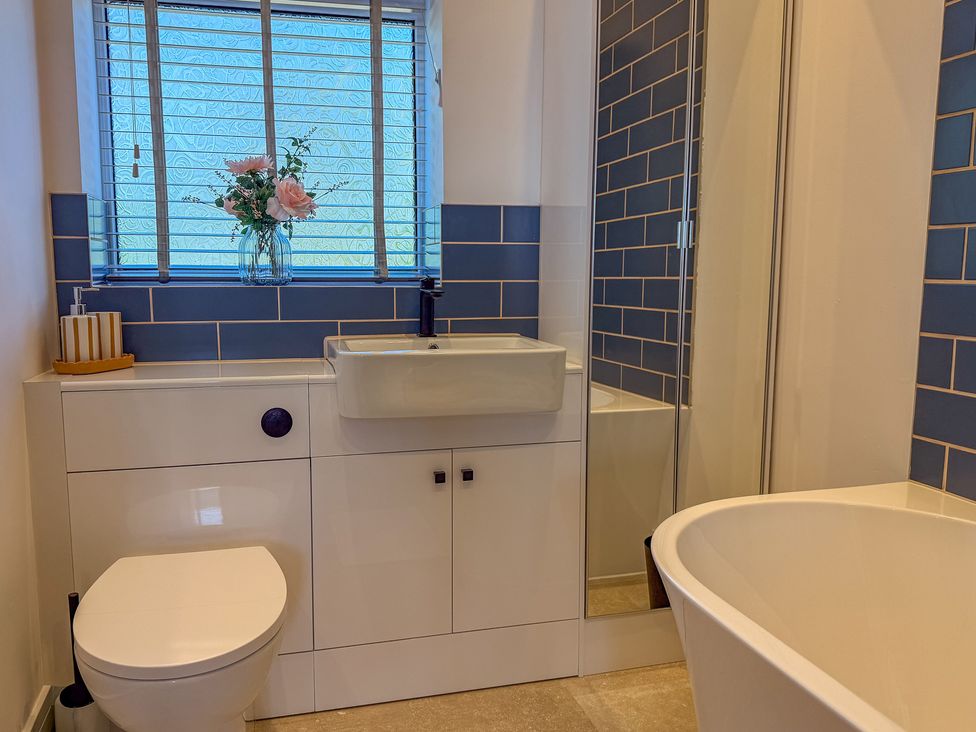 A bathroom featuring a sink, toilet, bathtub, and wall tiles at 4 Bryn Heulog in Wrexham
