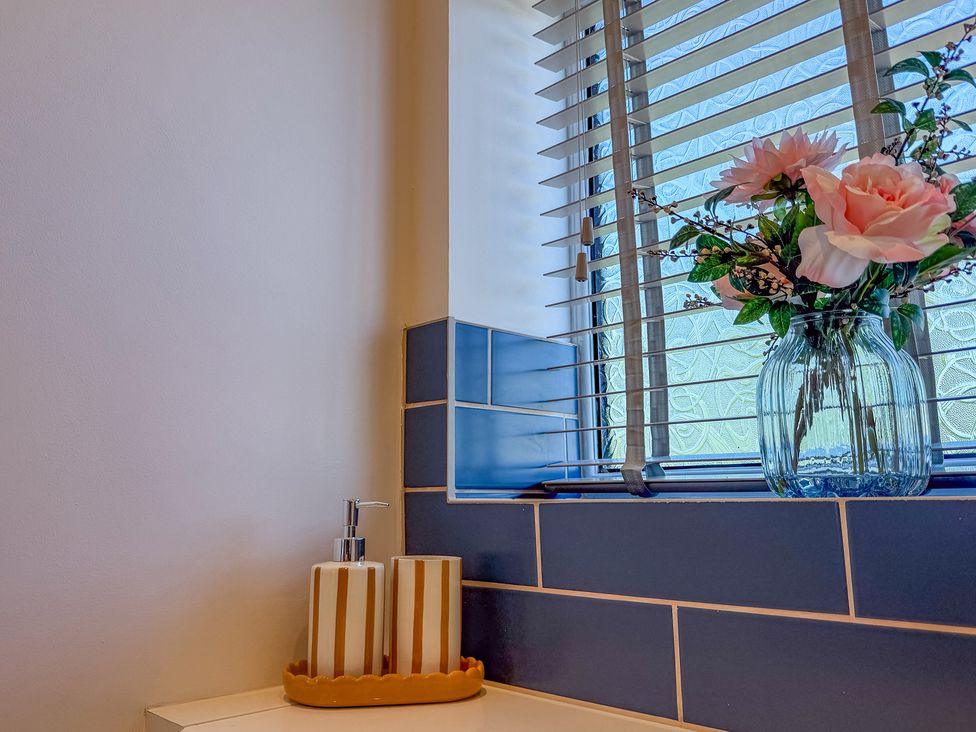 A bathroom with a soap dispenser and flowers by the window at 4 Bryn Heulog in Wrexham