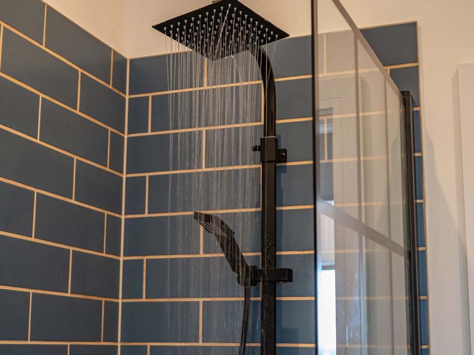 A shower with a rainfall shower head and tiled walls at 4 Bryn Heulog Wrexham