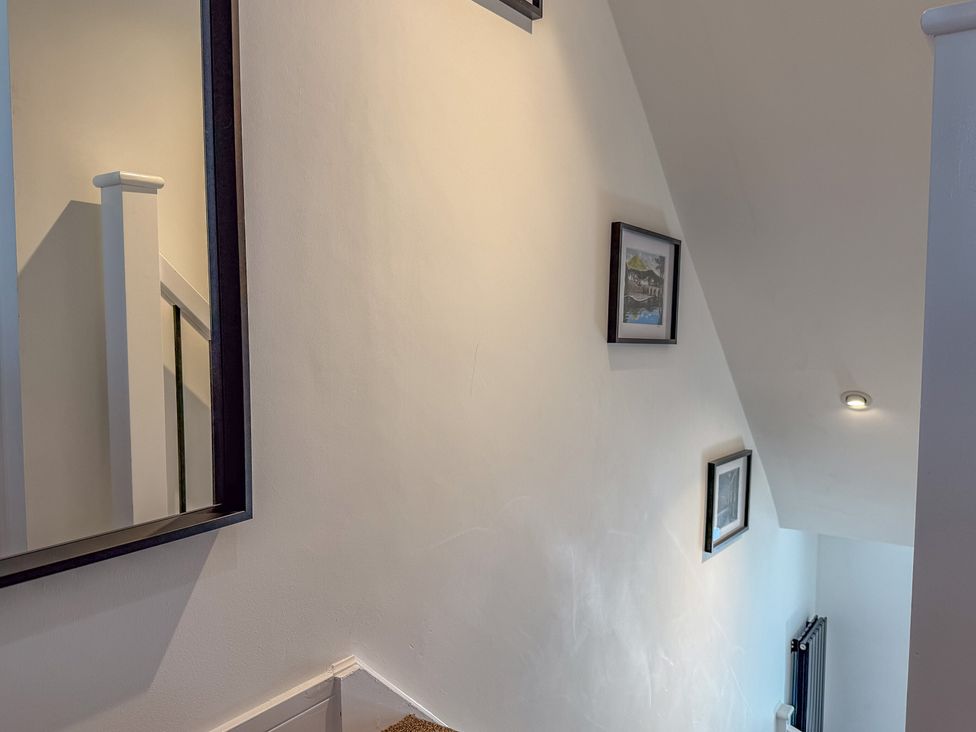 A staircase with a mirror and picture frames at 4 Bryn Heulog in Wrexham