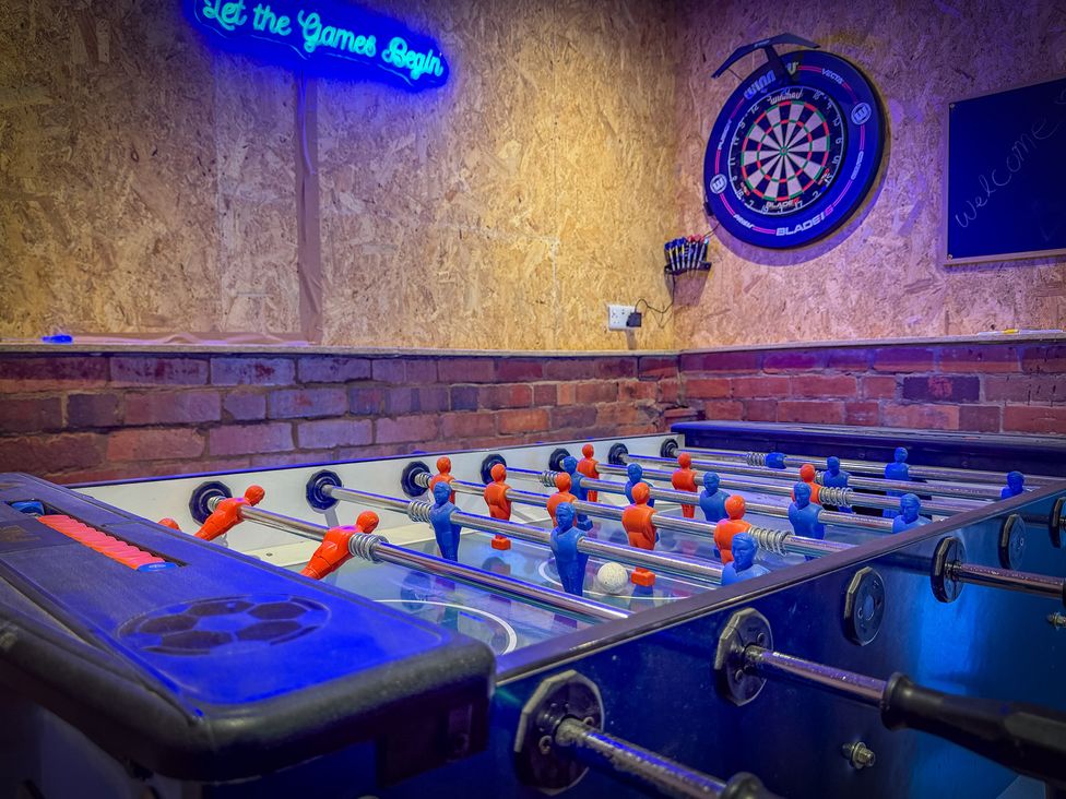 A foosball table with players and a dartboard at 4 Bryn Heulog, Wrexham