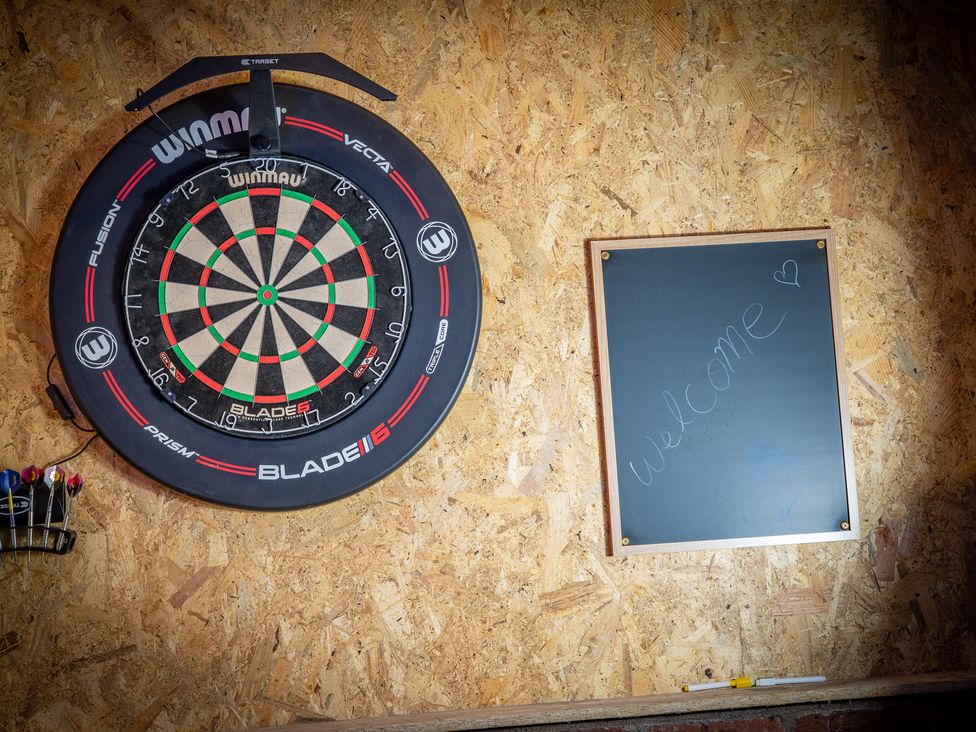 A dartboard and chalkboard in a game room at 4 Bryn Heulog in Wrexham