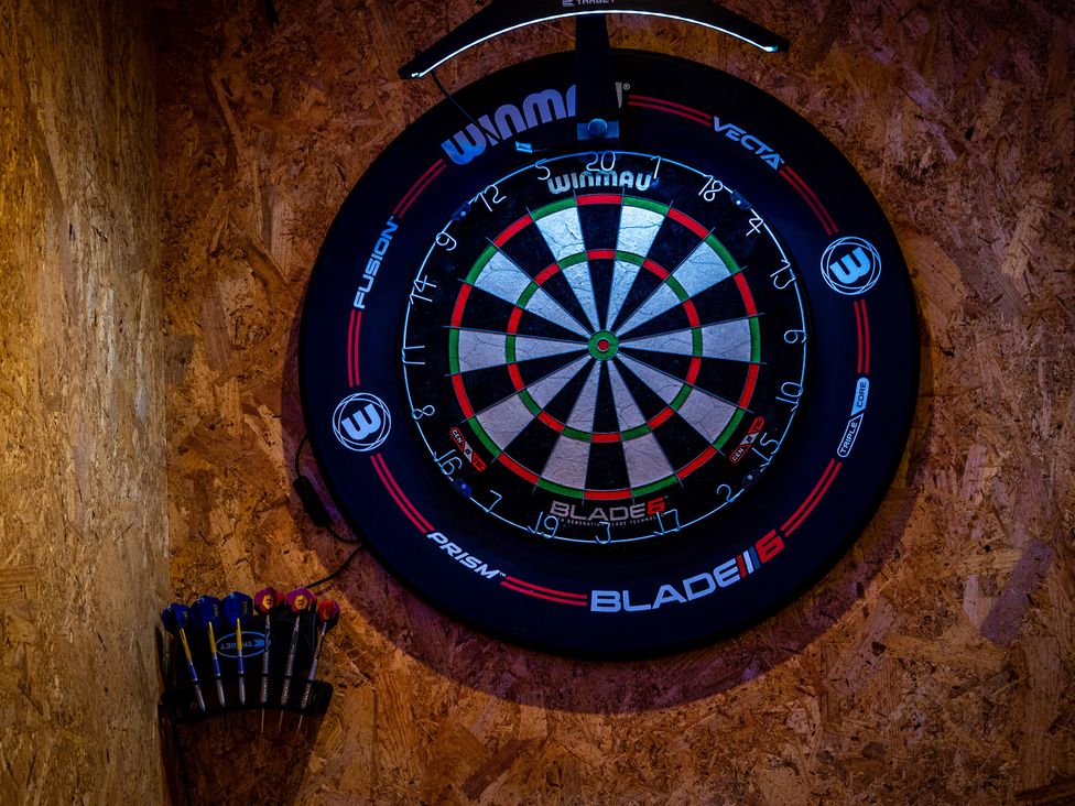 A dartboard mounted on the wall with darts in a game room at 4 Bryn Heulog in Wrexham