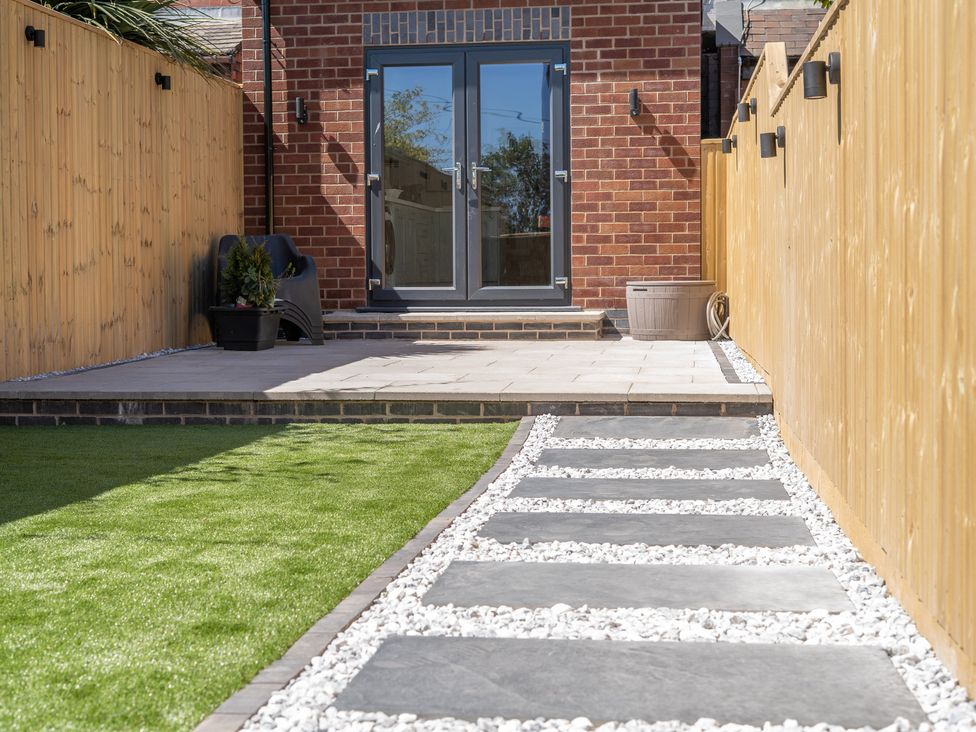 A garden with a patio, pathway, and plant at 4 Bryn Heulog Wrexham