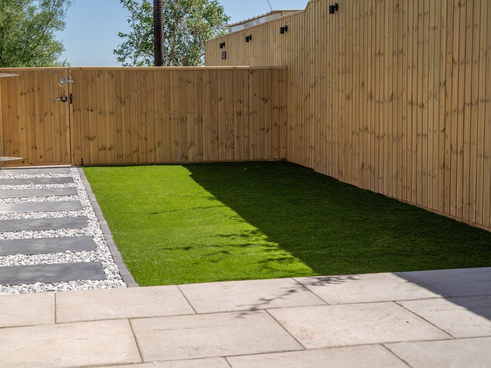 A garden with grass and paving stones at 4 Bryn Heulog in Wrexham