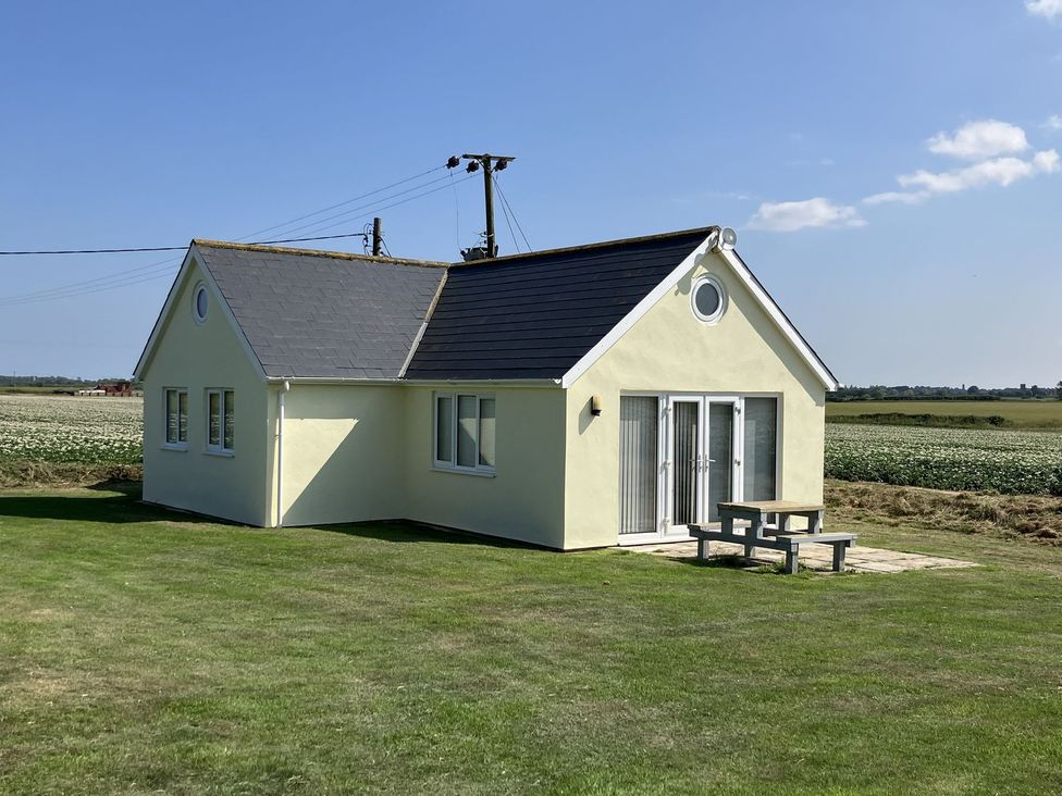 A house with a slate roof and a bench outside at Seadrift near Happisburgh