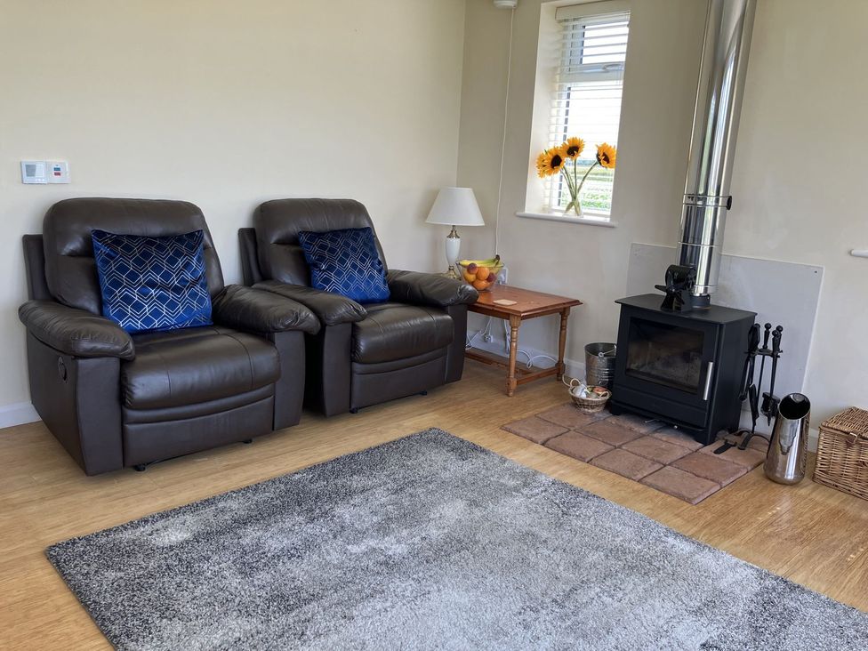 A living room with recliner chairs and a wood burning stove at Seadrift near Happisburgh