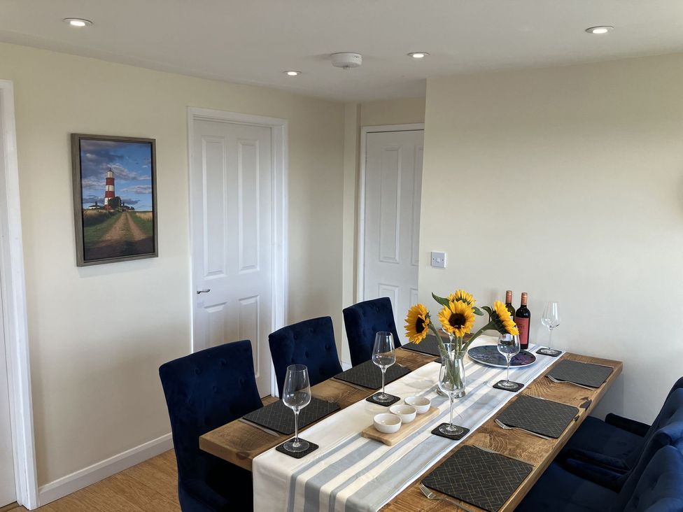 A dining room with a wooden table set for dinner at Seadrift in Bush Estate near Happisburgh