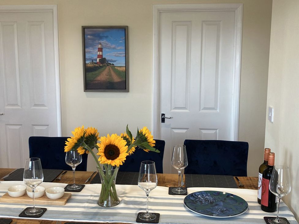 A dining room with sunflowers and wine bottles at Seadrift Bush Estate near Happisburgh
