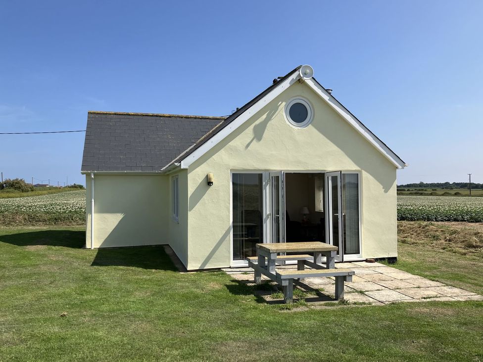 An outdoor view of a house with a table in front at Seadrift Bush Estate near Happisburgh