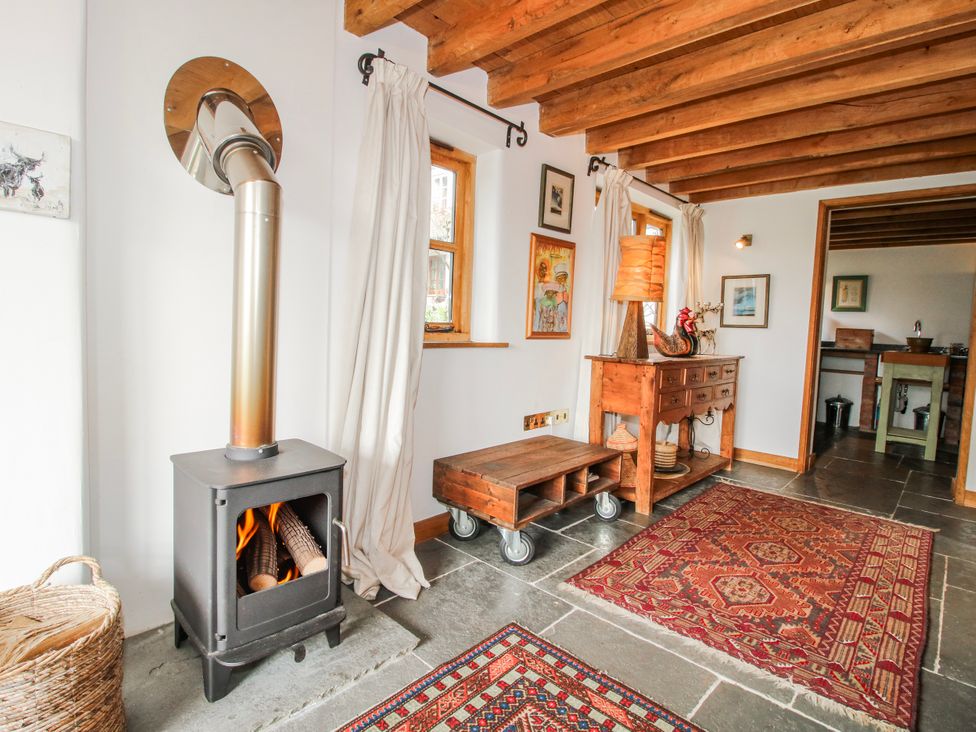 A living room with a wood stove and a table at Bell House Cottage in Wistanstow near Craven Arms