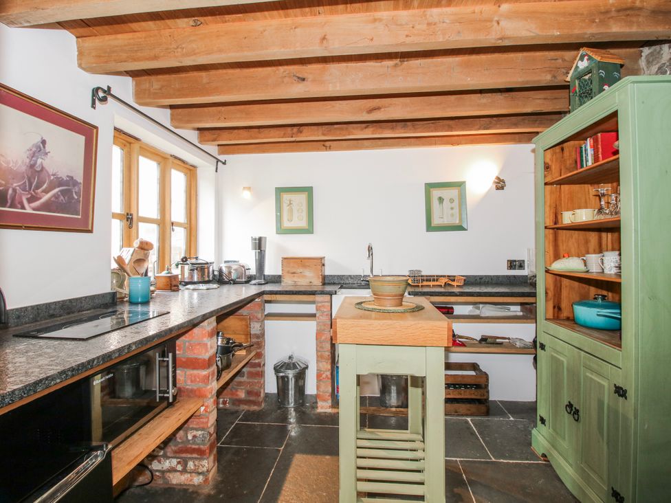 A kitchen with a wooden table and storage cabinet at Bell House Cottage in Wistanstow near Craven Arms