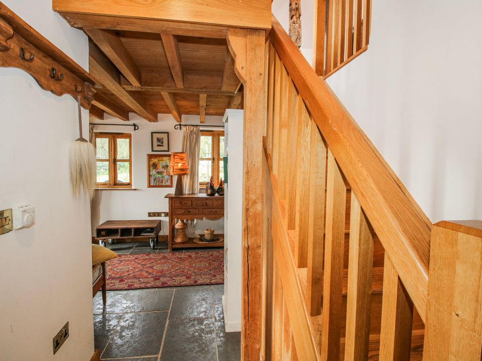 A hallway with a staircase and coat rack at Bell House Cottage Wistanstow near Craven Arms