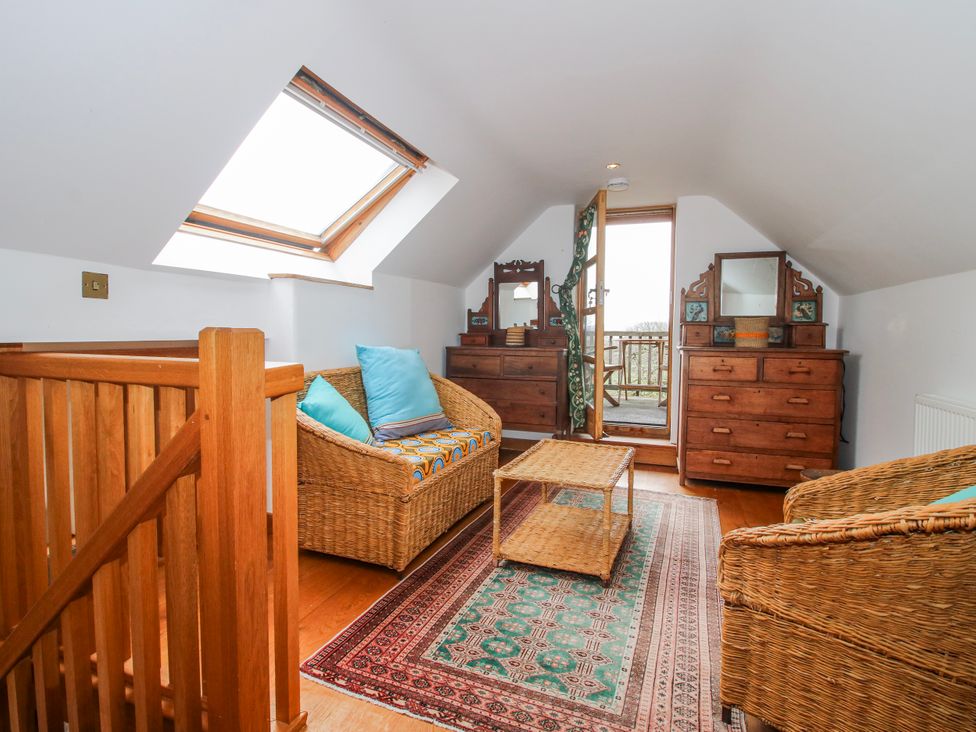 An attic with wicker furniture and a door leading outside at Bell House Cottage Wistanstow near Craven Arms