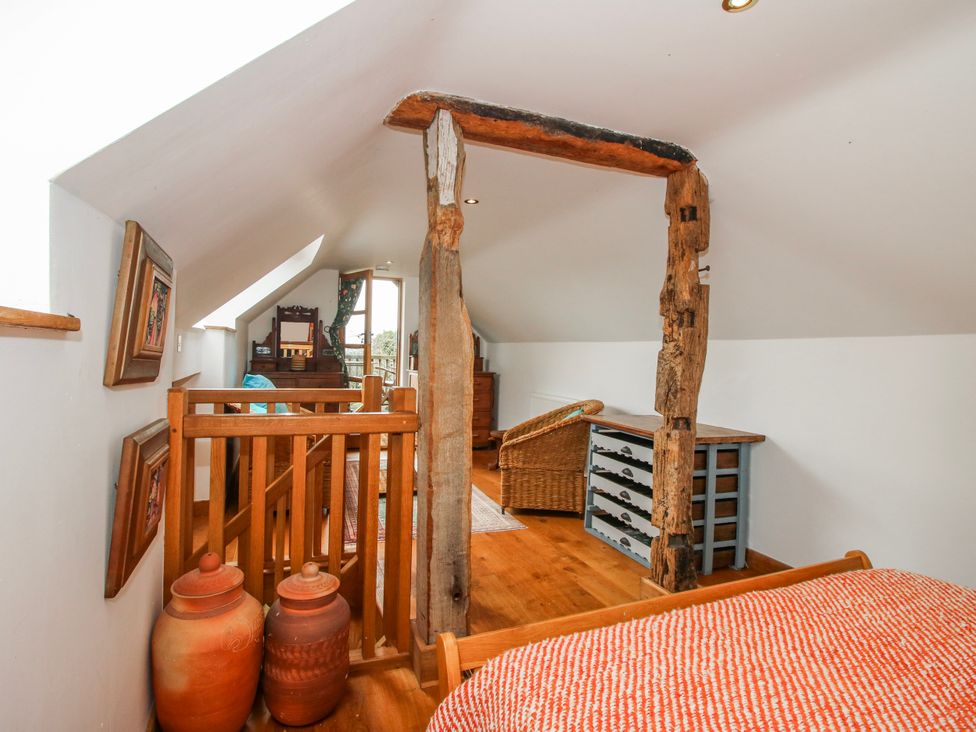 A loft with a bed and wooden railing at Bell House Cottage in Wistanstow near Craven Arms