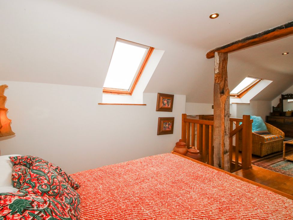 A bedroom with a bed, decorative pillows, and skylights at Bell House Cottage Wistanstow near Craven Arms